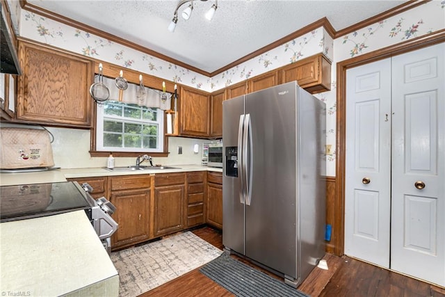 6215 Russwood Dr, Pleasant Garden, NC 27313 - kitchen featuring stainless steel appliances, a sink, brown cabinetry, crown molding, and dark wood-style flooring