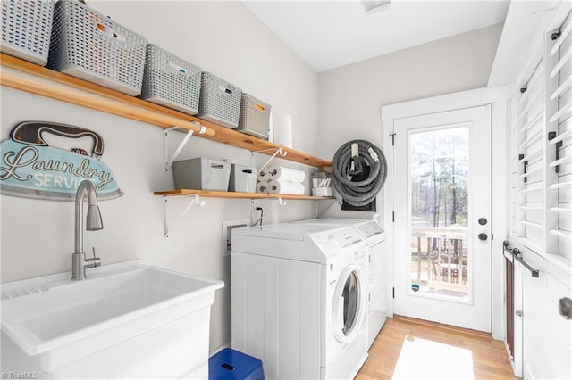 washroom featuring laundry area, light wood finished floors, a sink, and independent washer and dryer