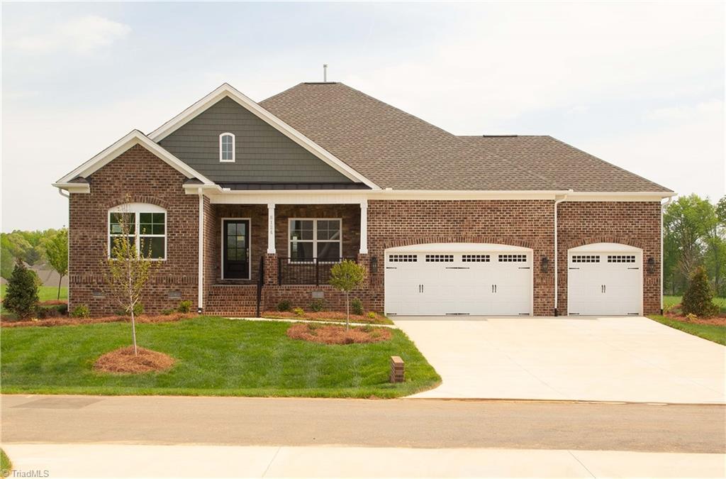 8124 Simon Dr Lot 48, Stokesdale, NC 27357 - view of front of property with a garage, brick siding, driveway, a front lawn, and covered porch