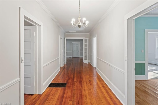 hall featuring french doors, dark wood-type flooring, crown molding, and a notable chandelier