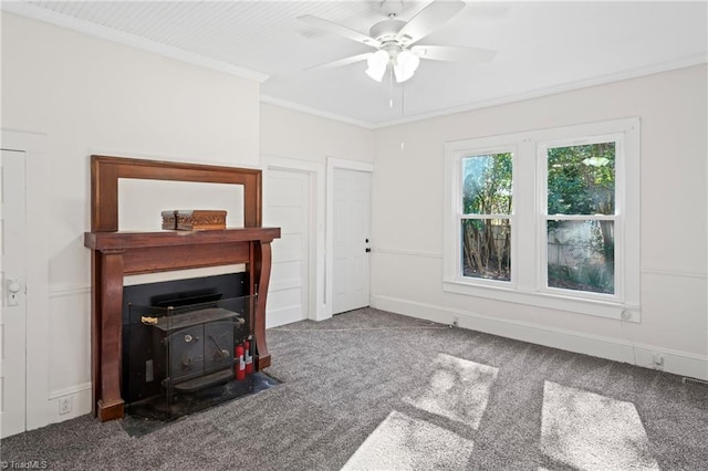 carpeted living room featuring ceiling fan, a wood stove, and ornamental molding