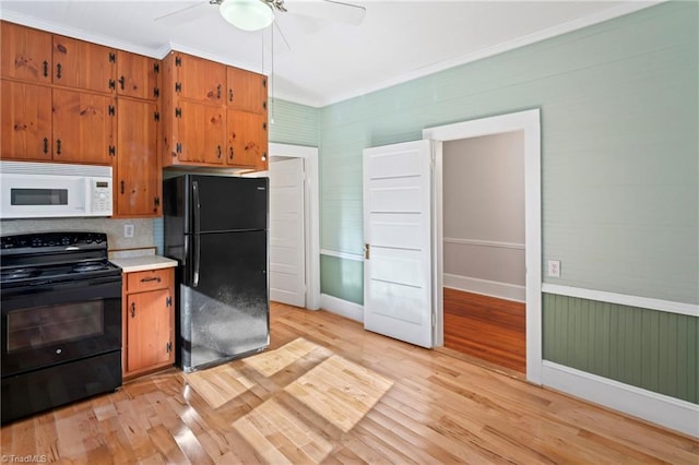 kitchen with decorative backsplash, light wood-type flooring, crown molding, and black appliances