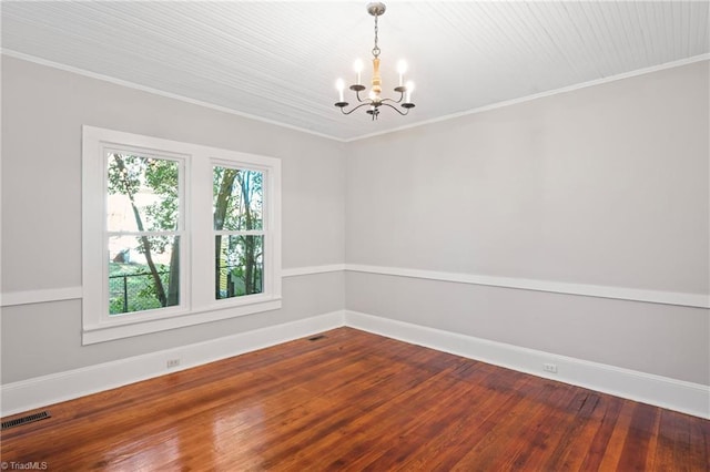 spare room featuring crown molding, hardwood / wood-style floors, and a notable chandelier