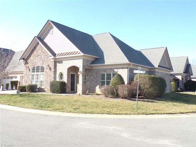 view of front of property with a standing seam roof, a front lawn, brick siding, and metal roof