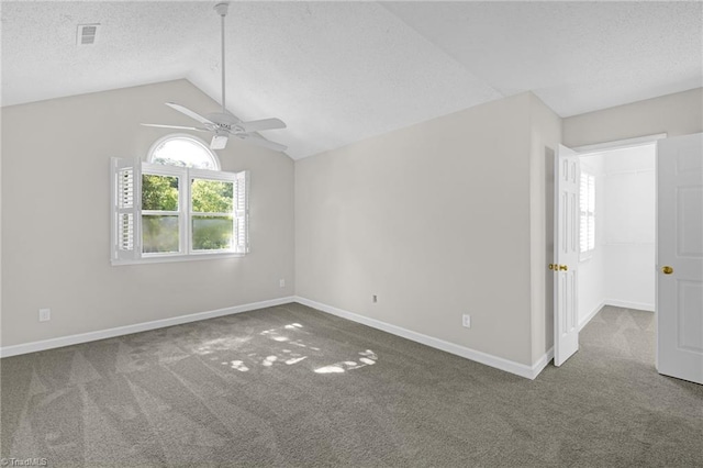 carpeted empty room featuring ceiling fan, visible vents, baseboards, and vaulted ceiling