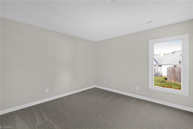 unfurnished room with baseboards, dark carpet, a textured ceiling, and visible vents