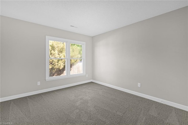 empty room with a textured ceiling, baseboards, and dark colored carpet