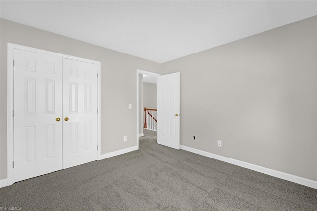 unfurnished bedroom featuring baseboards, a closet, and dark colored carpet