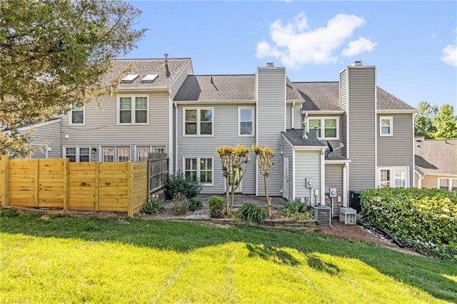 back of property featuring fence, central air condition unit, a chimney, and a yard