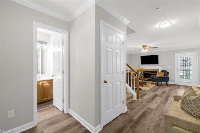 hall featuring baseboards, ornamental molding, wood finished floors, and stairway