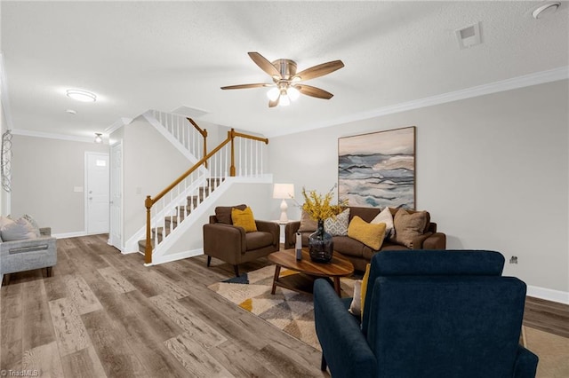 living room with visible vents, ornamental molding, wood finished floors, ceiling fan, and stairway