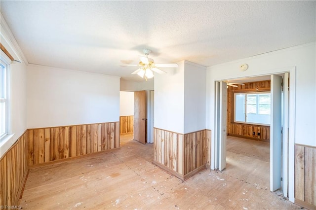 spare room featuring ceiling fan, a textured ceiling, and wooden walls