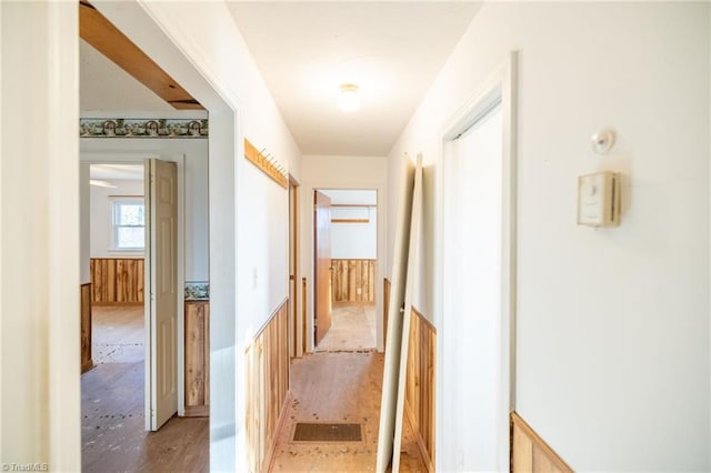 corridor featuring light wood-type flooring and wooden walls