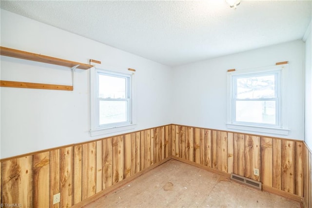 empty room with wooden walls and a textured ceiling