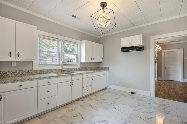 kitchen with sink, crown molding, hanging light fixtures, light stone countertops, and white cabinets