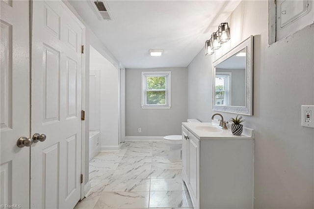 bathroom featuring vanity, a tub to relax in, and toilet