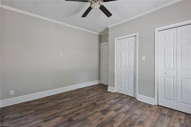 unfurnished bedroom with crown molding, dark wood-type flooring, two closets, and ceiling fan