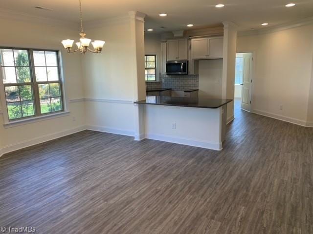 kitchen with tasteful backsplash, crown molding, pendant lighting, and dark hardwood / wood-style flooring