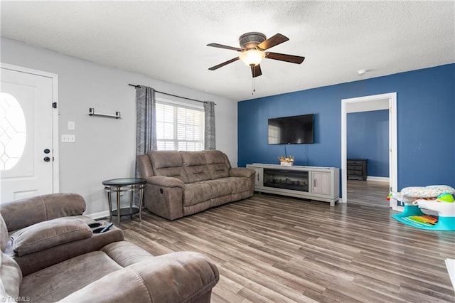 living room featuring ceiling fan, wood-type flooring, and a textured ceiling