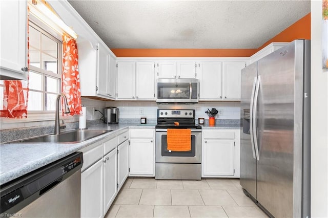 kitchen with stainless steel appliances, a textured ceiling, backsplash, sink, and white cabinetry