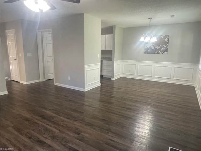 interior space featuring dark wood finished floors, ceiling fan with notable chandelier, and wainscoting
