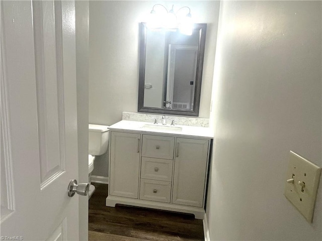 half bath with vanity, toilet, and wood finished floors