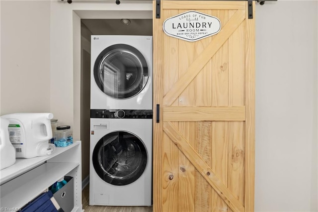 washroom featuring hardwood / wood-style floors, a barn door, and stacked washer / dryer