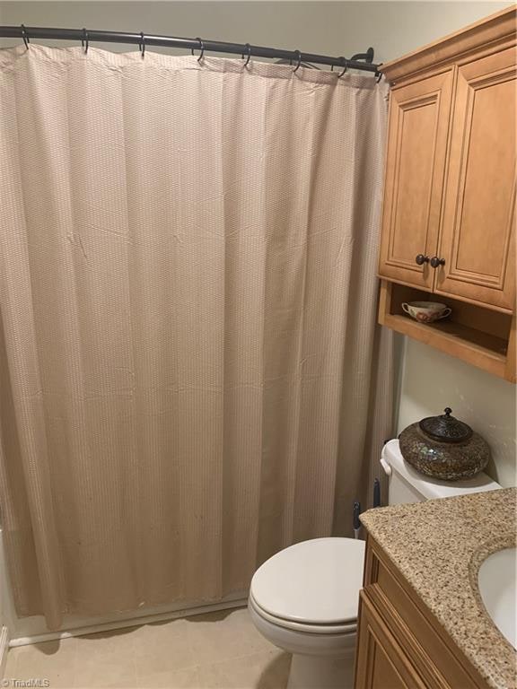 bathroom with toilet, vanity, and tile patterned flooring