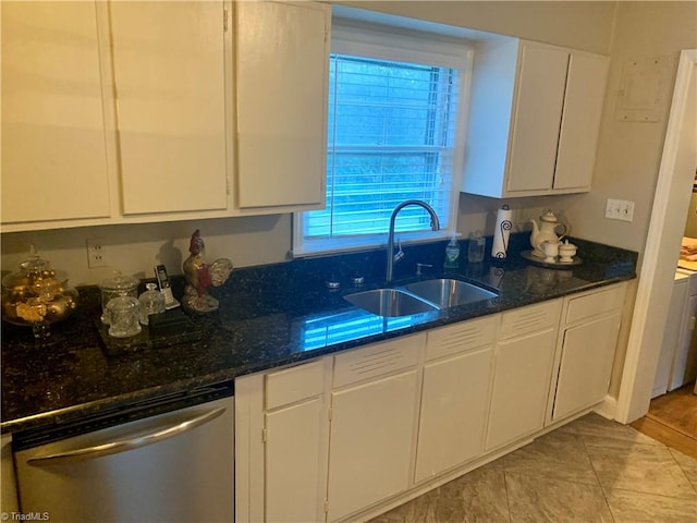 kitchen featuring stainless steel dishwasher, sink, white cabinetry, and dark stone counters