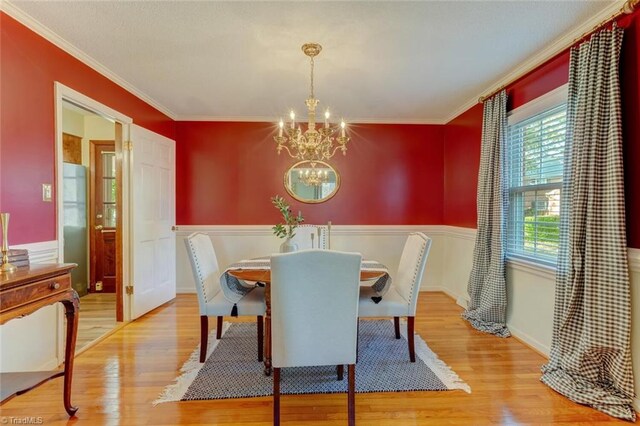 dining space featuring crown molding, an inviting chandelier, and light wood-type flooring