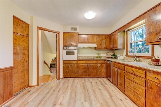 kitchen featuring sink, light hardwood / wood-style floors, a textured ceiling, oven, and dishwasher