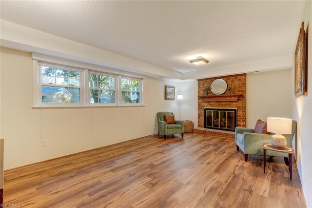 sitting room with light hardwood / wood-style floors and a brick fireplace