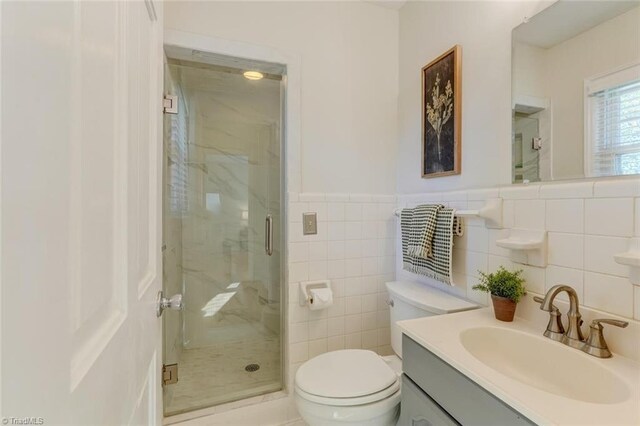 bathroom with vanity, an enclosed shower, toilet, and tile walls