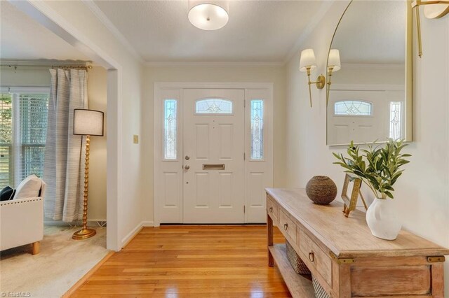 entryway with ornamental molding and light wood-type flooring