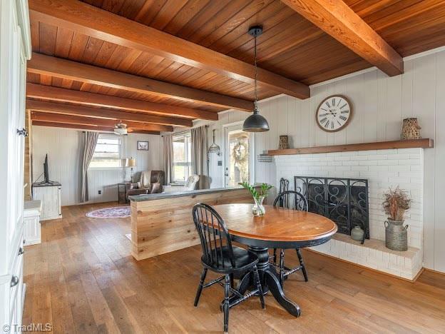 dining area with wood ceiling, a fireplace, beam ceiling, and hardwood / wood-style flooring