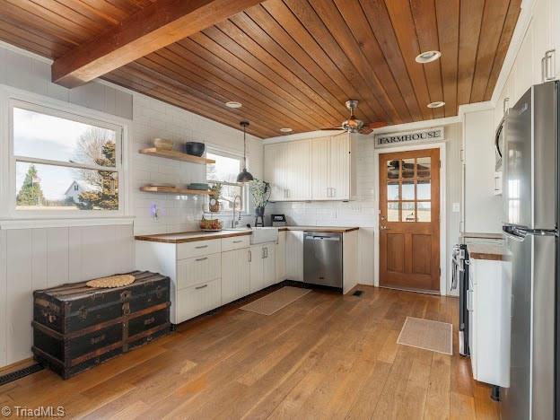 kitchen with stainless steel appliances, tasteful backsplash, wood ceiling, white cabinets, and wood finished floors