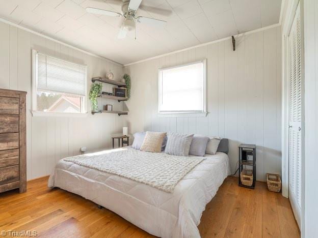 bedroom featuring light wood finished floors, a ceiling fan, and crown molding