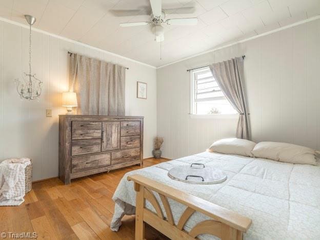 bedroom with ceiling fan, ornamental molding, and wood finished floors