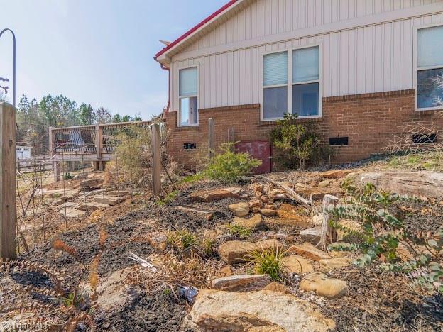 view of side of property featuring crawl space and brick siding