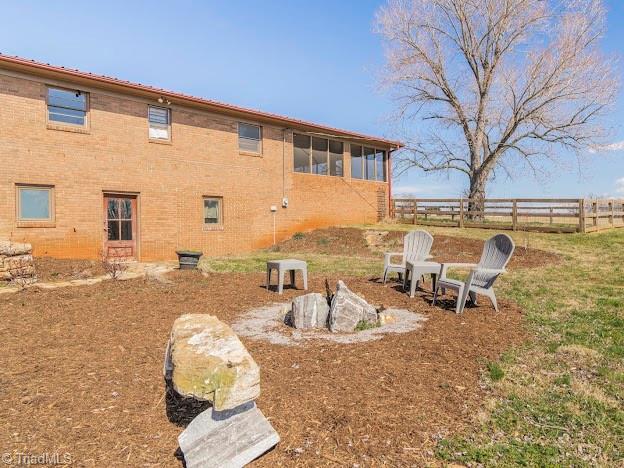 rear view of house featuring brick siding and fence