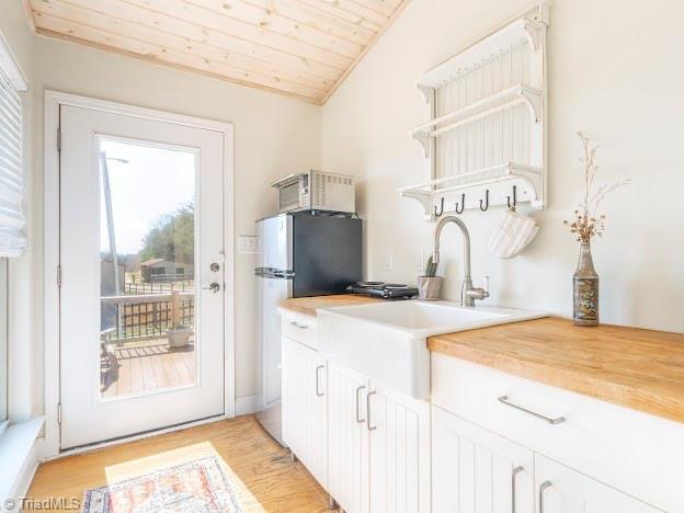 kitchen with open shelves, lofted ceiling, light wood-style floors, wood counters, and wooden ceiling