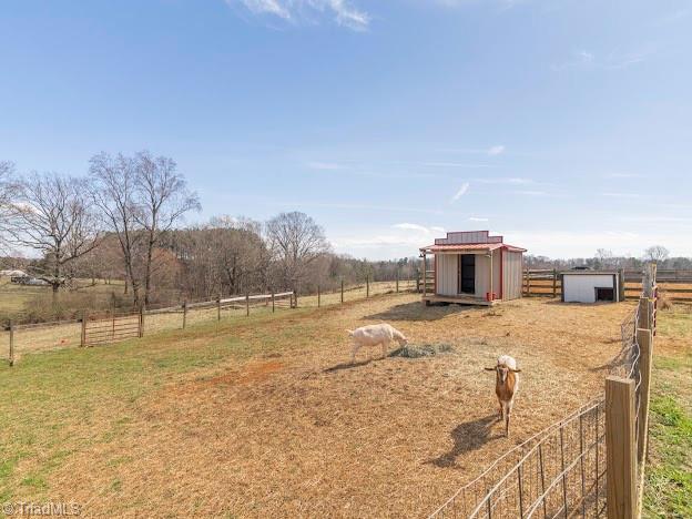 view of yard with a rural view, an outdoor structure, and fence