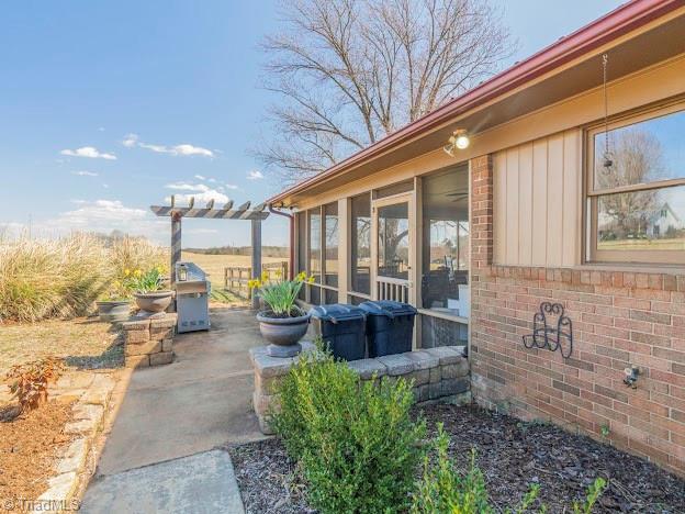 view of patio / terrace with a sunroom and a pergola