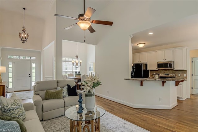 3001 Walbrook Ter, Browns Summit, NC 27214 - living area featuring a chandelier, wood finished floors, baseboards, ceiling fan, and a high ceiling