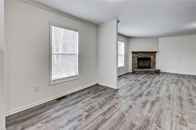 unfurnished living room with a stone fireplace, ornamental molding, and light hardwood / wood-style floors