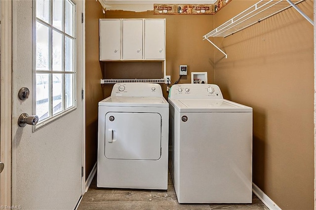 clothes washing area with cabinets, separate washer and dryer, and light wood-type flooring