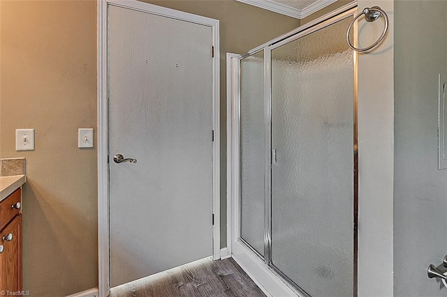 bathroom with vanity, an enclosed shower, hardwood / wood-style flooring, and crown molding