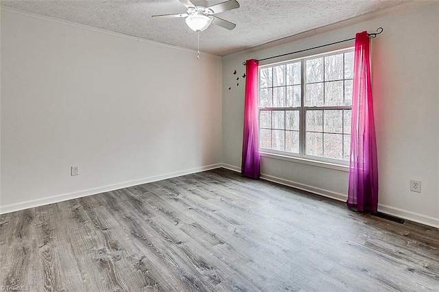 empty room with ceiling fan, a wealth of natural light, a textured ceiling, and light wood-type flooring