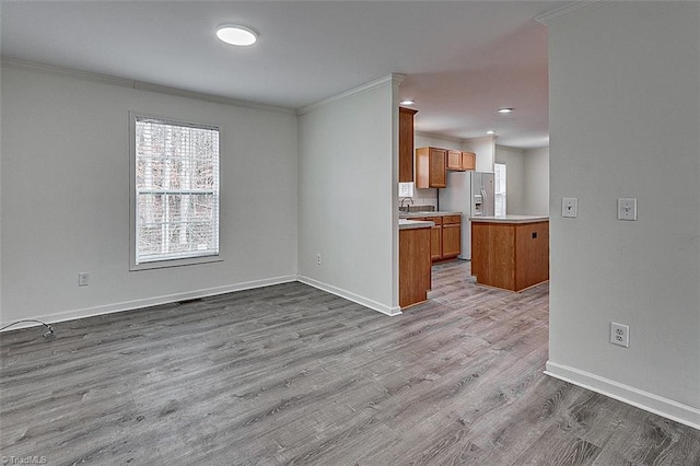 kitchen with crown molding, plenty of natural light, stainless steel fridge with ice dispenser, and light wood-type flooring