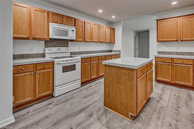 kitchen with crown molding, white appliances, a center island, and light hardwood / wood-style flooring